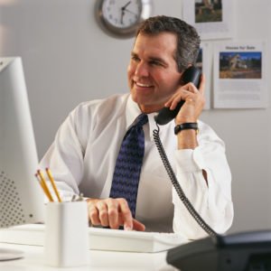 Businessman on Phone While Using Computer